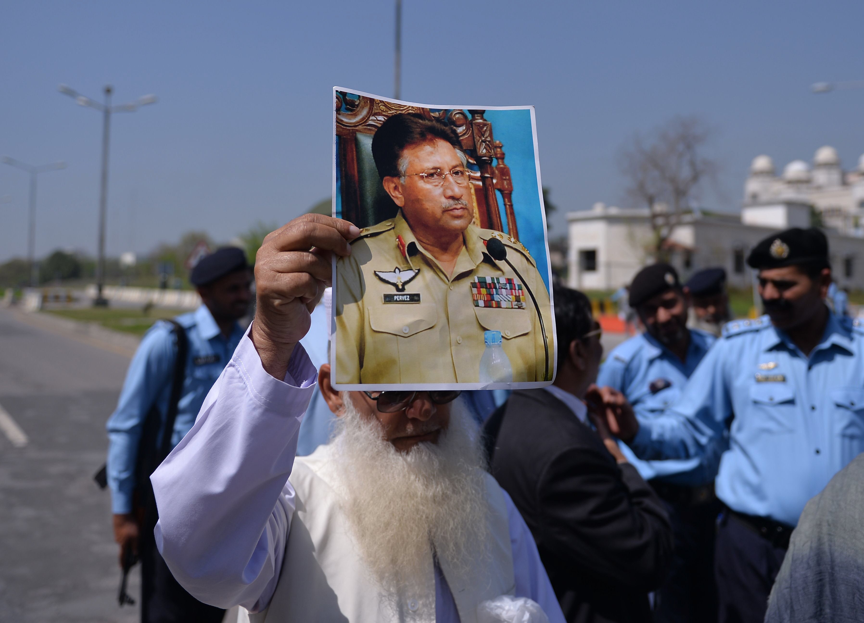 a supporter of pervez musharraf holds a poster bearing his image outside a special court set up to try musharraf during a hearing in islamabad on march 31 2014 photo afp