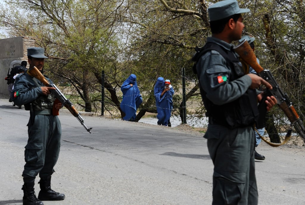 afghan policemen stand guard as residents walk along a street on the outskirts of the northwestern city of herat photo afp