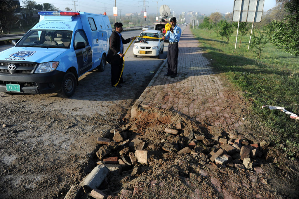 policemen roll barricade tape at the site of a bomb explosion targetting musharraf in islamabad on april 3 2014 photo afp