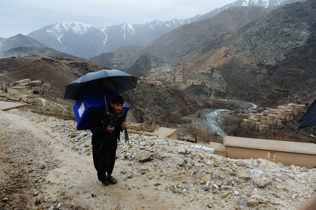an afghan villager carries election materials over his back as he hikes to his village along a country road high in the mountains of shutul district in northern afghanistan photo afp