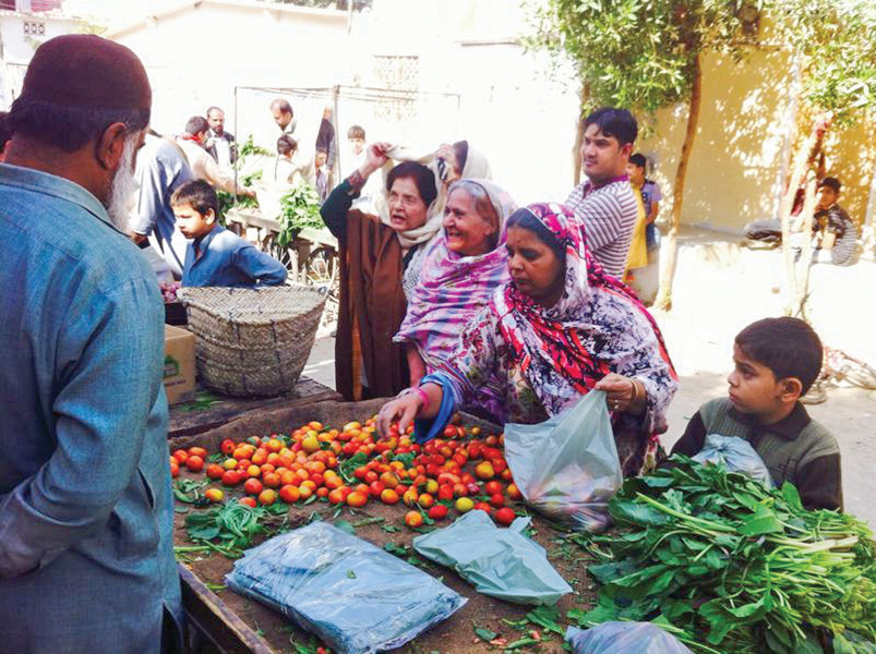 a wooden board shows the price list of the items for the day right a cart full of tomatoes that are being sold at subsidised prices at the bazaar set up by the boys above photo courtesy kamran niazi