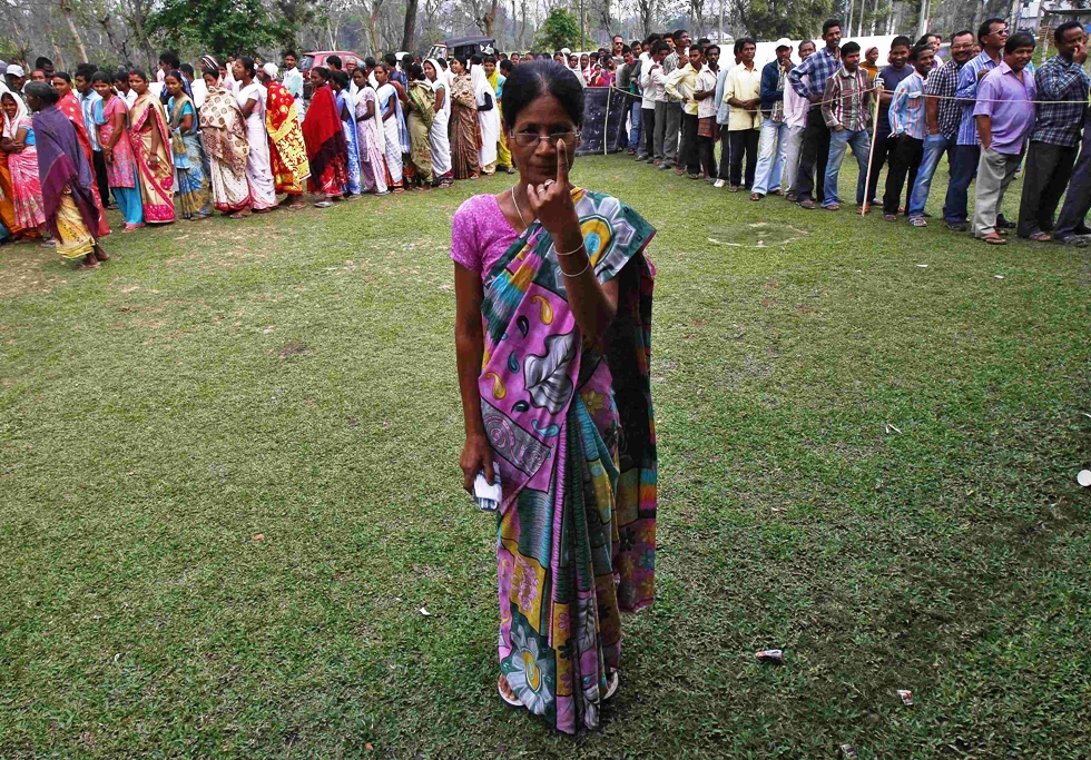 a woman shows her ink marked finger after casting her vote as others line up to cast their ballot at a polling station in nakhrai village in tinsukia district in the northeastern indian state of assam april 7 2014 photo reuters