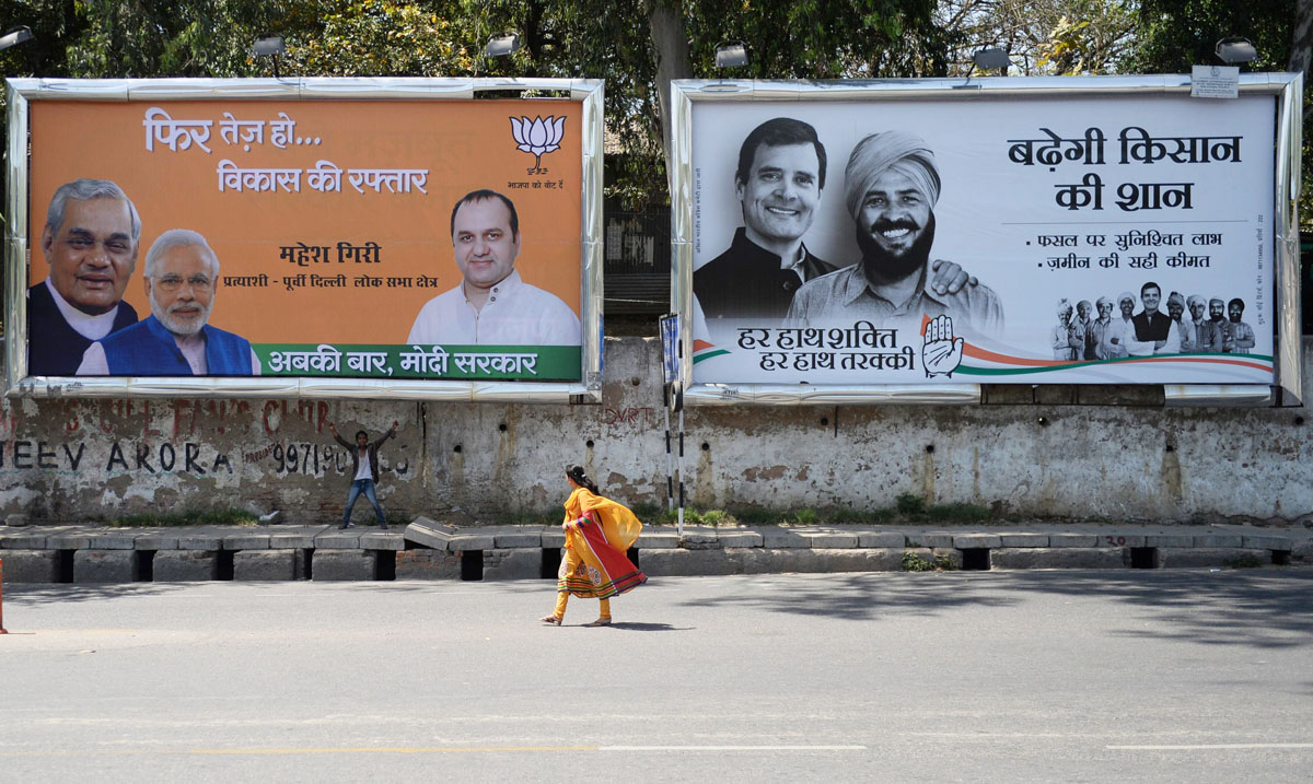 an indian walks past election campaign hoardings of the opposition bharatiya janata party l and congress r in new delhi on april 8 2014 ahead of the second phase of national elections scheduled for april 10 photo afp