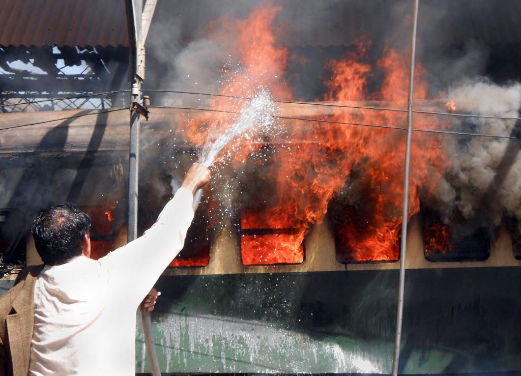 a pakistani railway official extinguishes fire after a bomb blast on a train at the sibi railway station some 160 kilometres south of its destination quetta on april 8 2014 photo afp