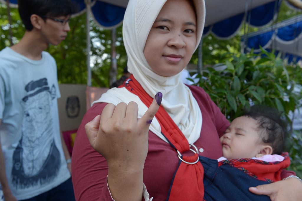 a young family leaves a polling station during legislative elections in jakarta on april 9 2014 photo afp