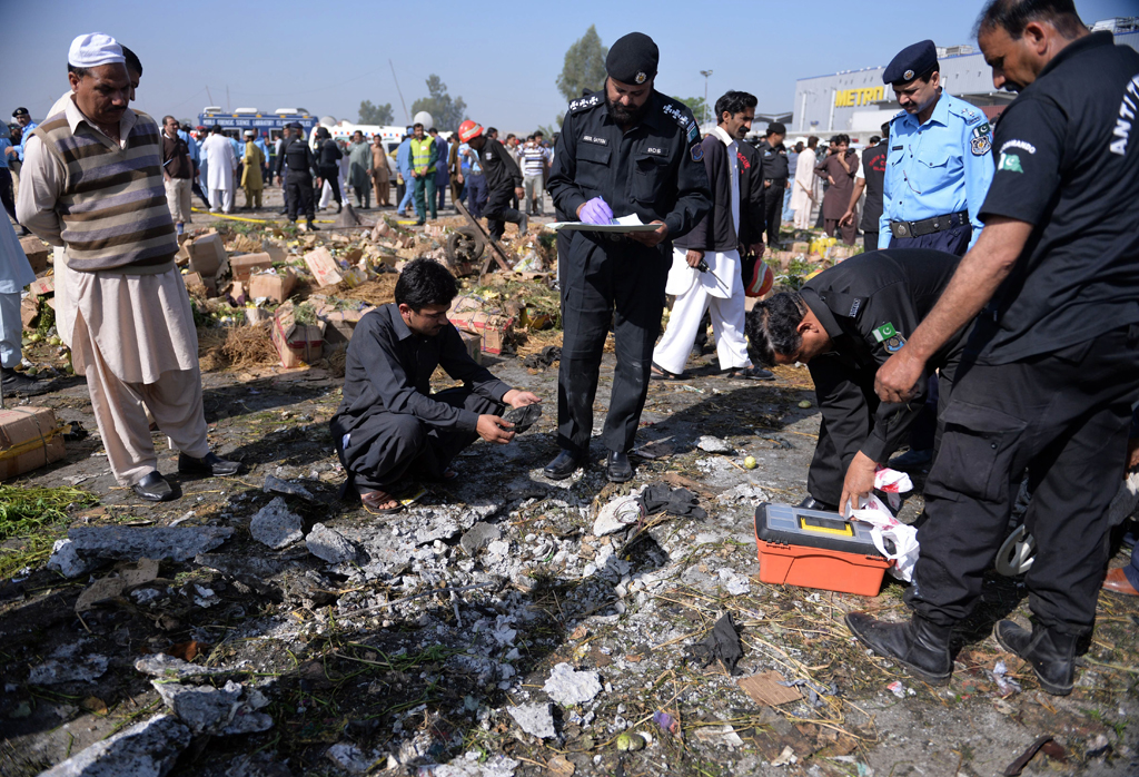 pakistani security officials inspect the site of a bomb explosion in a fruit and vegetable market in islamabad on april 9 2014 photo afp