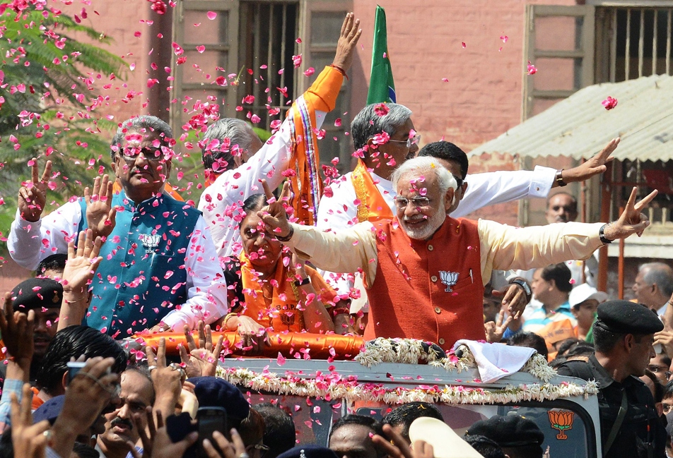 in this photograph taken on april 9 2014 chief minister of the western indian state of gujarat and bhartiya janta party bjp prime ministerial candidate narendra modi c is showered with flower petals during his roadshow in vadodara some 110 kms from ahmedabad prior to filing his nomination papers for the forthcoming elections photo afp