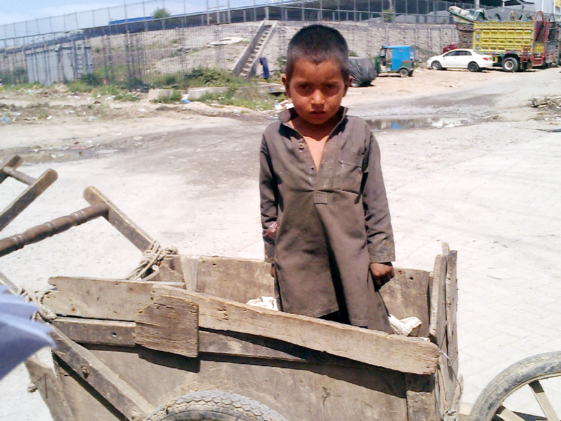 sitting in an empty pushcart with coat of dirt and dust over his dress and bare feet four year old raj muhammad s condition tells a story which is similar to millions of poverty stricken children in the country photo express