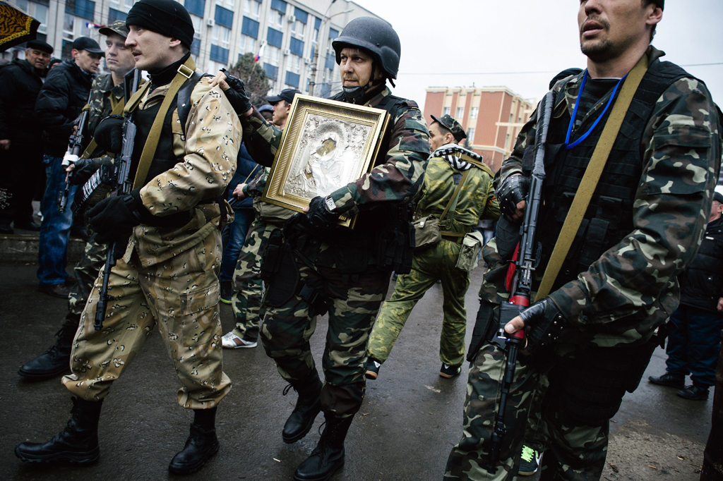 armed pro russian supporters carry an eastern orthodox icon of mary magdalene outside the secret service building in the eastern ukrainian city of lugansk on april 13 2014 photo afp