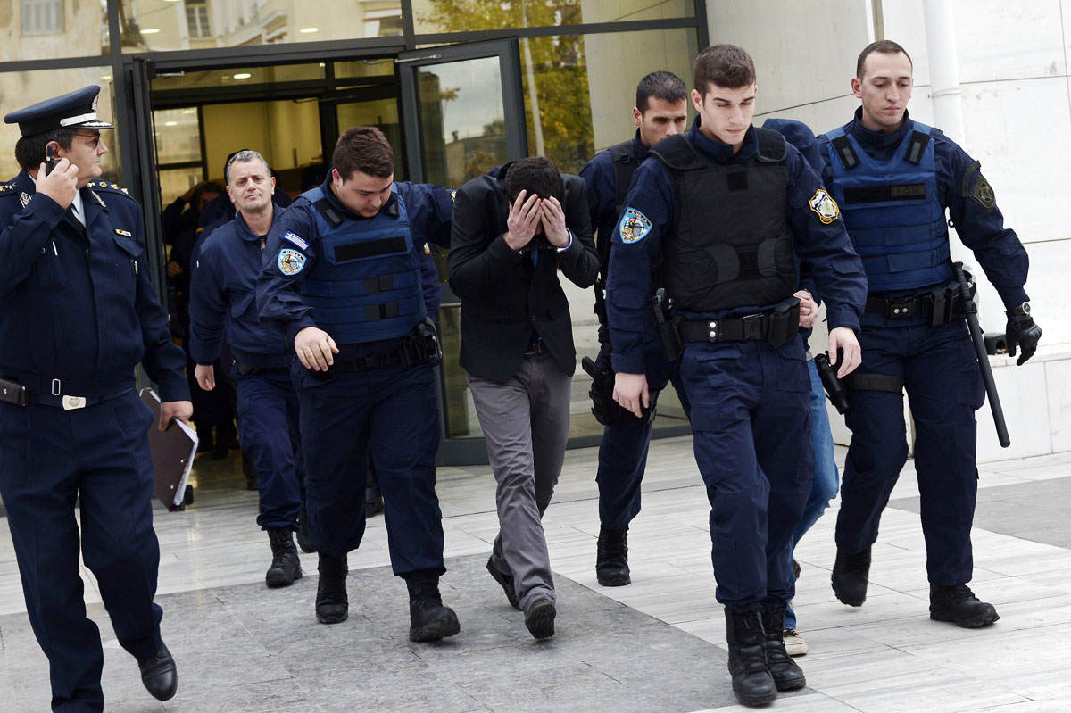 police officers escort one of the two suspected members of the greek neo nazi party golden dawn accused of stabbing a 27 year old pakistani man to death in athens on december 18 2013 photo afp file