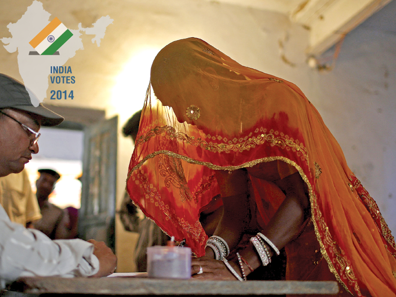 a polling official checks the identity of a voter inside a polling station in ajmer district in the desert indian state of rajasthan photo reuters