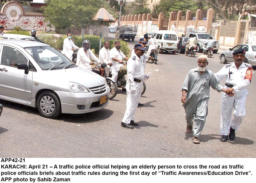 a traffic police personnel helps an elderly man cross the street at a traffic signal the traffic police department is running a campaign to raise awareness regarding traffic rules and road safety guidelines photo app