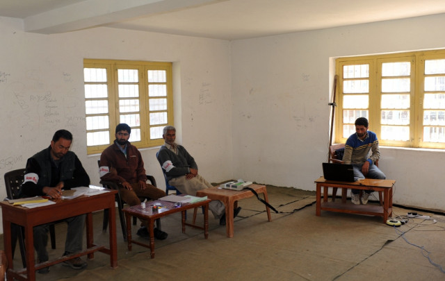 polling officials wait inside an empty polling station in tral area of anantnag contituency in indian administered kashmir on april 24 2014 during polling for national elections photo afp