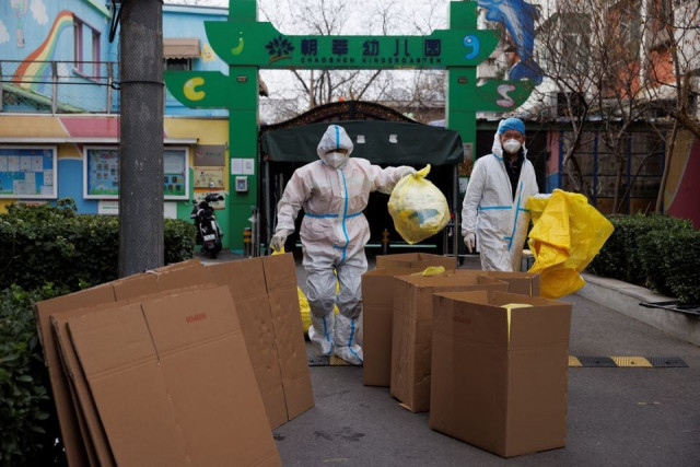 epidemic prevention workers in protective suits put medical waste into boxes in a residential compound as outbreaks of the coronavirus disease covid 19 continue in beijing china november 27 2022 reuters thomas peter
