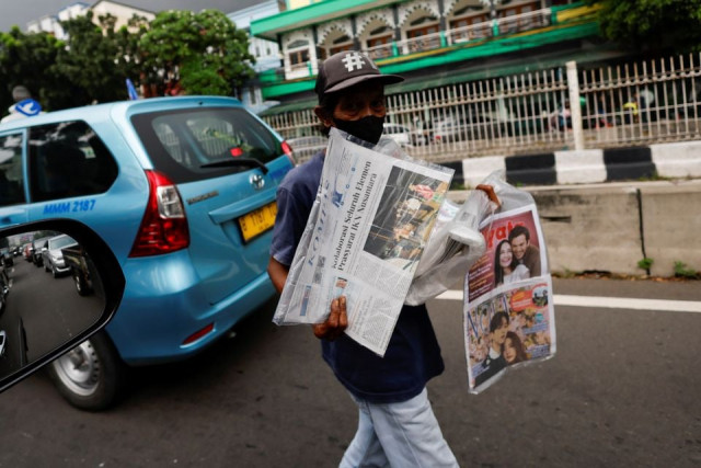 a street vendor sells papers with the news of indonesian new capital nusantara ikn on its headline during a traffic in jakarta march 15 2022 reuters willy kurniawan file photo