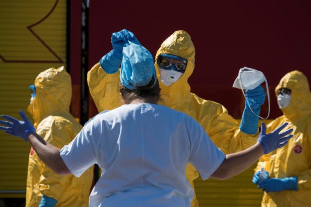 Firemen remove protective gear from medical staff after they load a COVID-19 patient onto a French Air Force plane at the Bale-Mulhouse airport. PHOTO: AFP 