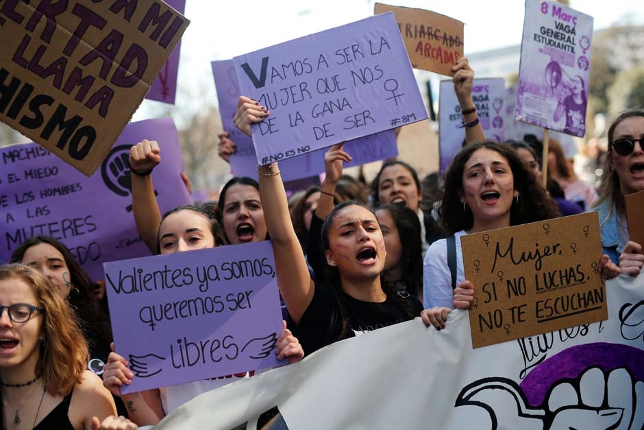 Student protesters shout slogans while holding signs reading 