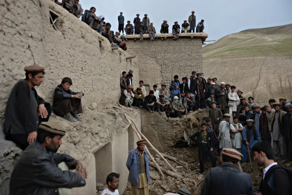 afghan villagers look on as rescuers search desperately for survivors trapped under the mud in argo district of badakhshan province on after a massive landslide buried a village photo afp