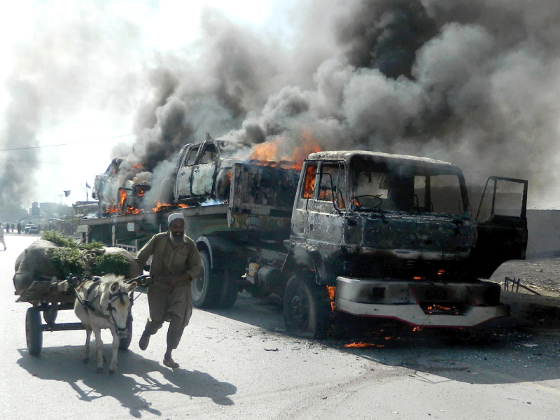 a man leads his donkey cart past a burning truck transporting nato vehicles photo afp