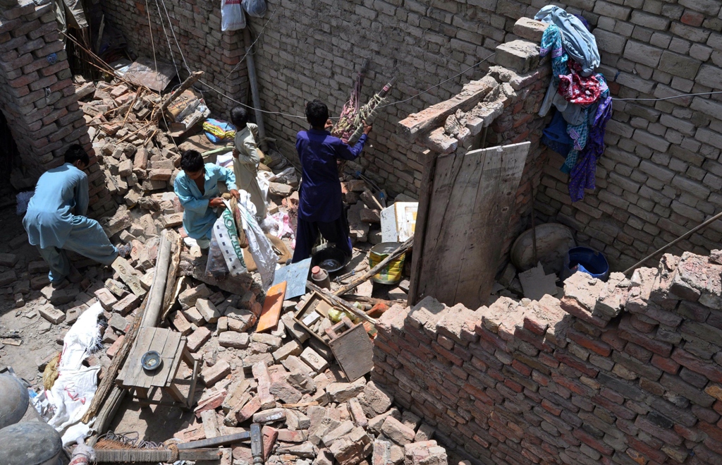 earthquake survivors remove their belongings from the rubble of a damaged house in nawabshah photo afp