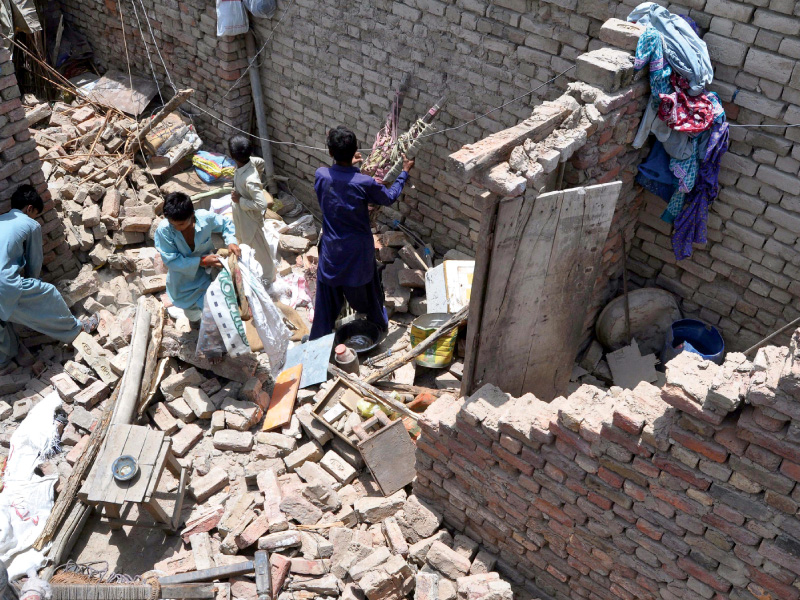 earthquake survivors remove their belongings from the rubble of a damaged house in nawabshah photo afp