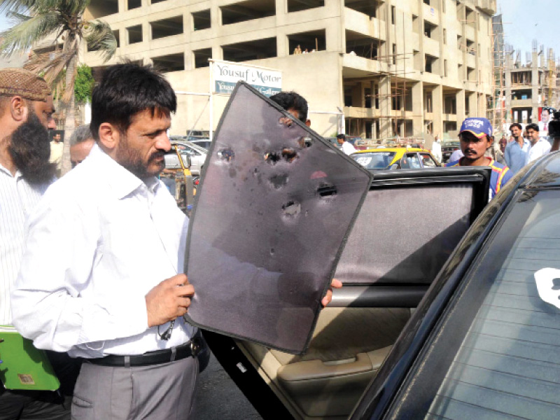 an investigator examines the bullet ridden sun screen of the vehicle of jpmc mlo dr manzoor memon who was shot dead by unidentified gunmen in delhi colony on tuesday photo rashid ajmeri express