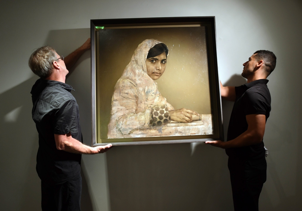 workers hang a painting by jonathan yeo titled quot girl reading malala yousafzai quot before the start of the auction may 14 2014 at christie 039 s afternoon session of post war and contemporary art in new york photo afp