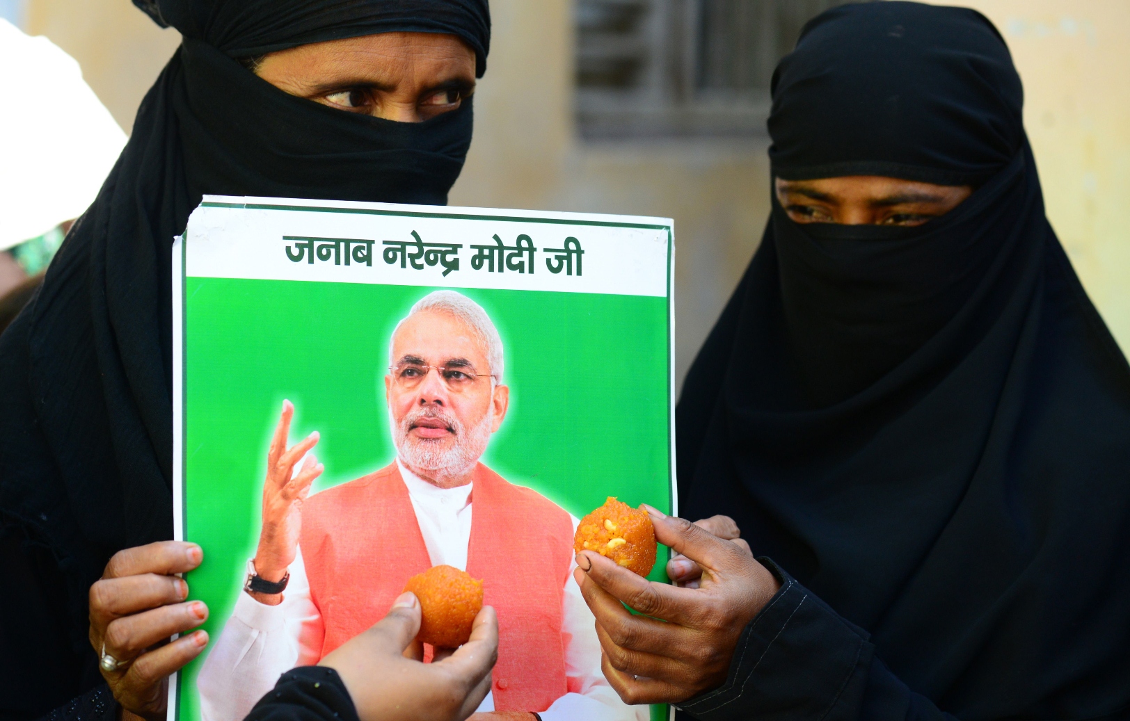 indian muslim women hold up sweets and a portrait of victorious bharatiya janata party bjp prime ministerial candidate narendra modi in varanasi on may 16 2014 photo afp