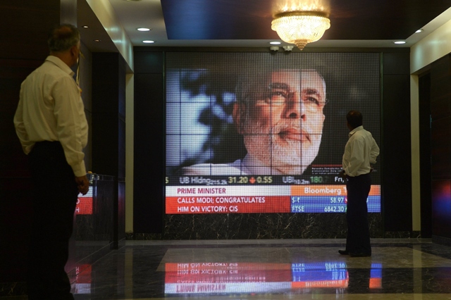 in this photograph taken on may 16 2014 indian passers by watch an image of bharatiya janata party bjp prime ministerial candidate narendra modi on a digital broadcast screen at the entrance of the bombay stock exchange bse building in mumbai bharatiya janata party leader and hindu nationalist narendra modi stormed to victory at the polls in india 039 s general election throwing the left leaning secular congress from office and handing his party a powerful mandate for promised sweeping reforms photo afp