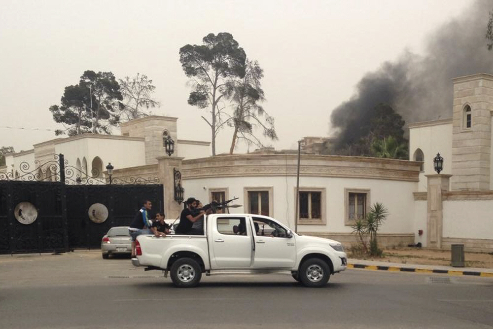 armed men aim their weapons from a vehicle as smoke rises in the background near the general national congress in tripoli photo reuters