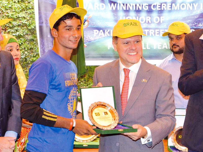 one of the players receives a shield from the brazilian ambassador left earlier the boys played a friendly match with a local team photo express afp