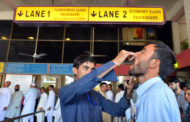 a health worker administers polio vaccination drops to a traveller at the peshawar international airport photo afp a health worker administers polio vaccination drops to a traveller at the peshawar international airport photo afp