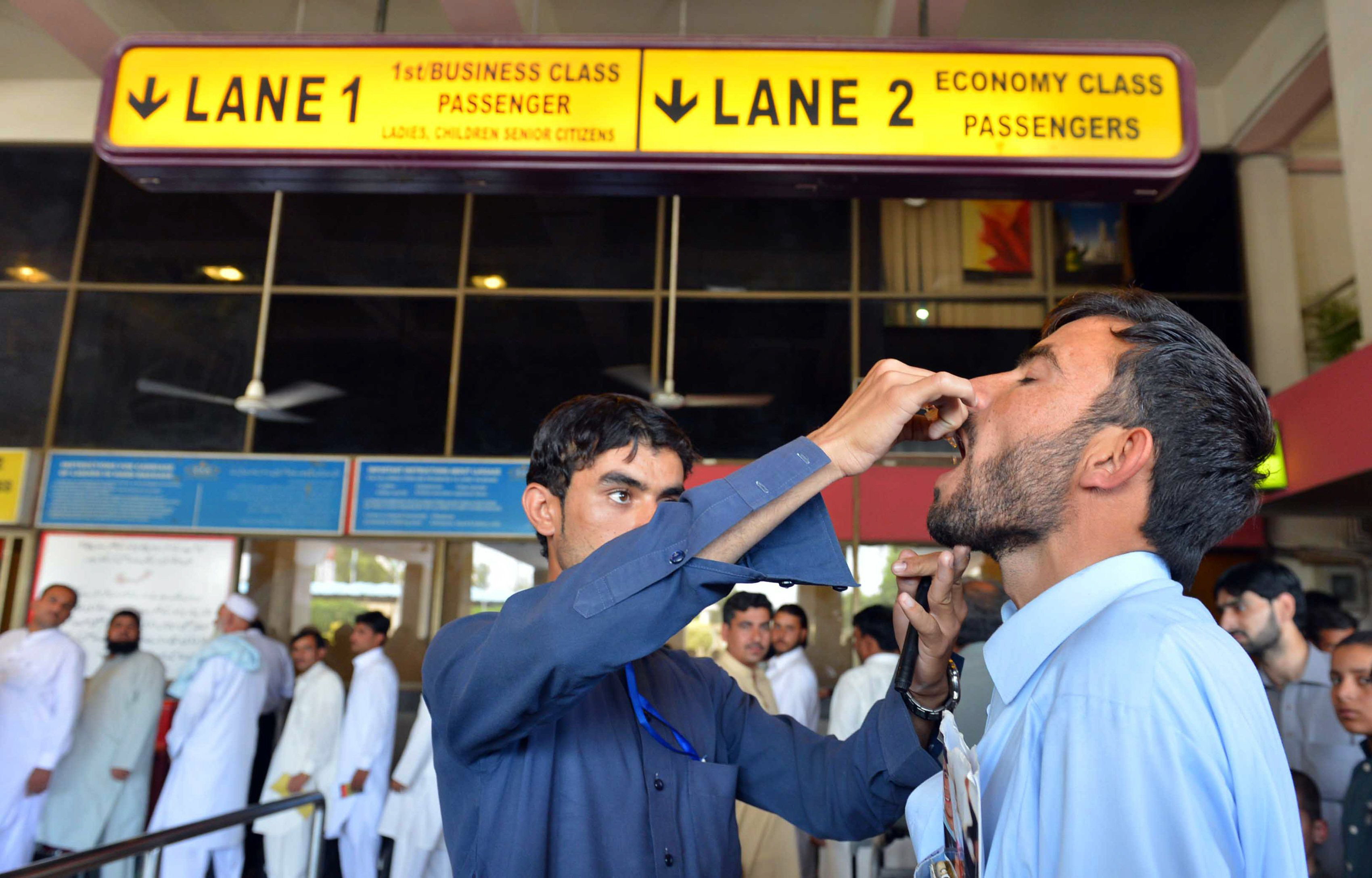 a health worker administers polio vaccination drops to a traveller at the peshawar international airport photo afp