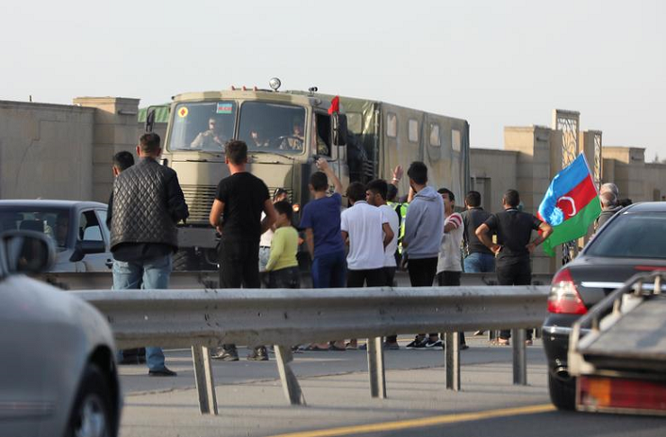 People line up along the roadside to greet Azerbaijani service members, who drive a truck in Baku, Azerbaijan, September 27. PHOTO: REUTERS