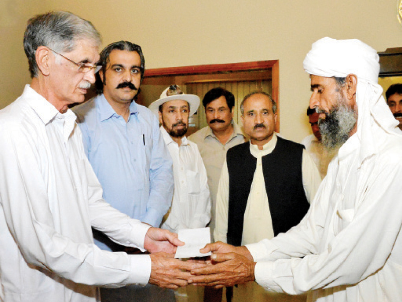 chief minister pervez khattak presenting cheques to affected families of the chashma sugar mill incident in di khan photo nni