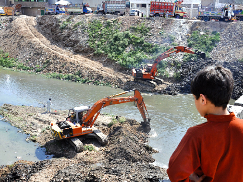 a boy watches an excavator at work in the leh photo zafar aslam express