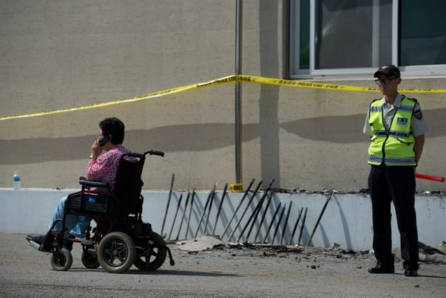 a woman in a wheelchair passes a policeman outside the fire damaged hyosarang hospital near janseong on may 28 2014 photo afp a woman in a wheelchair passes a policeman outside the fire damaged hyosarang hospital near janseong on may 28 2014 photo afp