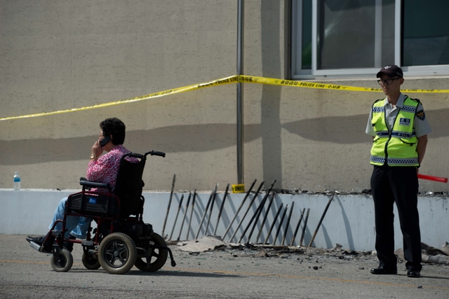 a woman in a wheelchair passes a policeman outside the fire damaged hyosarang hospital near janseong on may 28 2014 photo afp