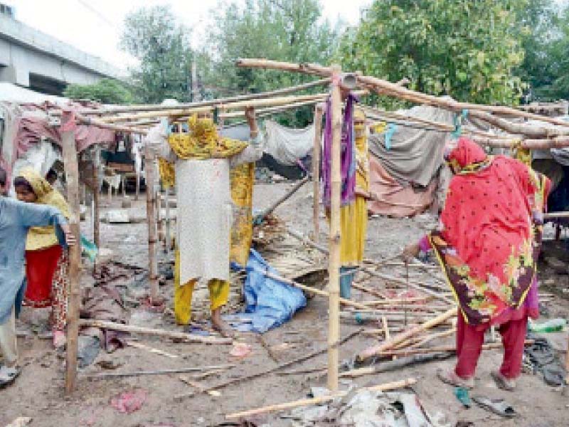 women fix their makeshift house which had collapsed after heavy rain on ring road in peshawar photo app