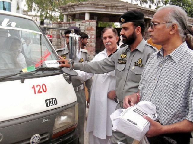 a police official pastes the sticker on a van photo muhammad javaid express a police official pastes the sticker on a van photo muhammad javaid express