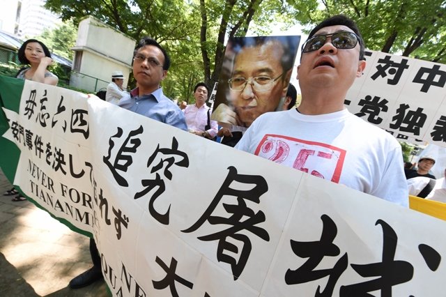 former chinese dissident leader wu 039 er kaixi r and activists hold a banner and a poster of jailed nobel peace prize laureate liu xiaobo as they march during a rally in tokyo on june 1 2014 ahead of the 25th anniversary marking the brutal crushing of the tiananmen square protests photo afp