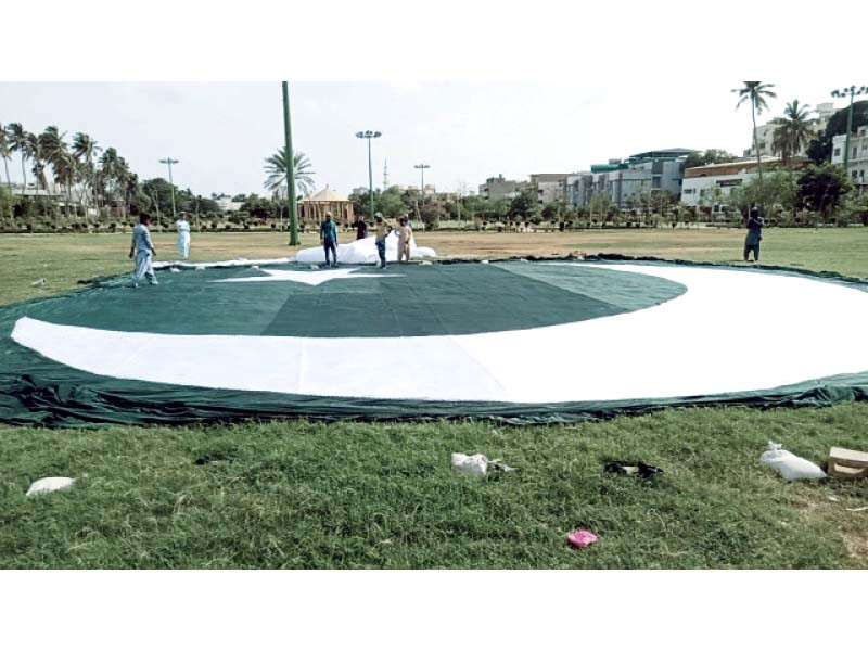 workers busy in preparing a huge national flag as part of independence day preparation at a park in karachi on monday photo express