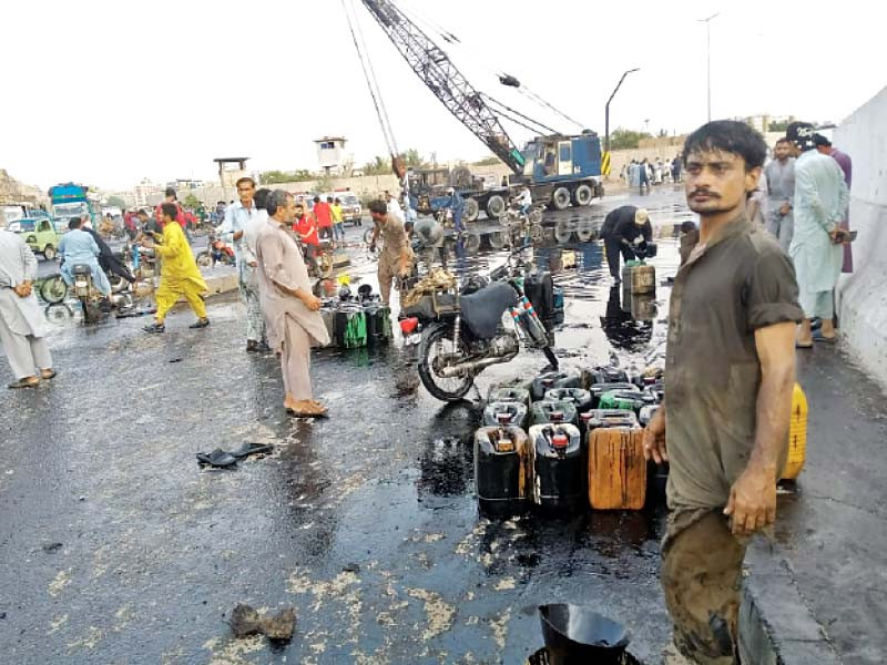 people collect oil spilled from a tanker which overturned on a road near the jinnah bridge in the keamari area on saturday photo express