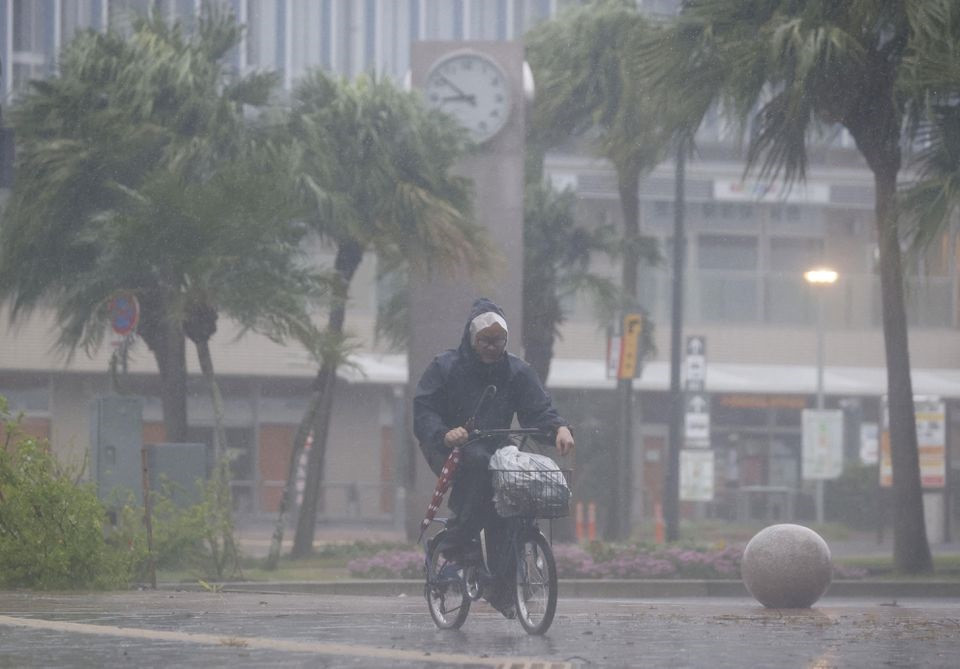 A man on a bicycle rides past in the heavy rain and wind caused by Typhoon Nanmadol in Miyazaki on Japan's southernmost main island of Kyushu September 18, 2022, in this photo taken by Kyodo. Mandatory credit Kyodo via REUTERS