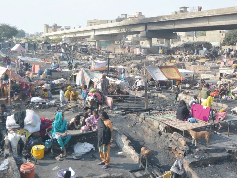 people on friday salvage whatever items they can after the devastating fire that charred the shanties under the teen hatti bridge on thursday night photo jalal qureshi express