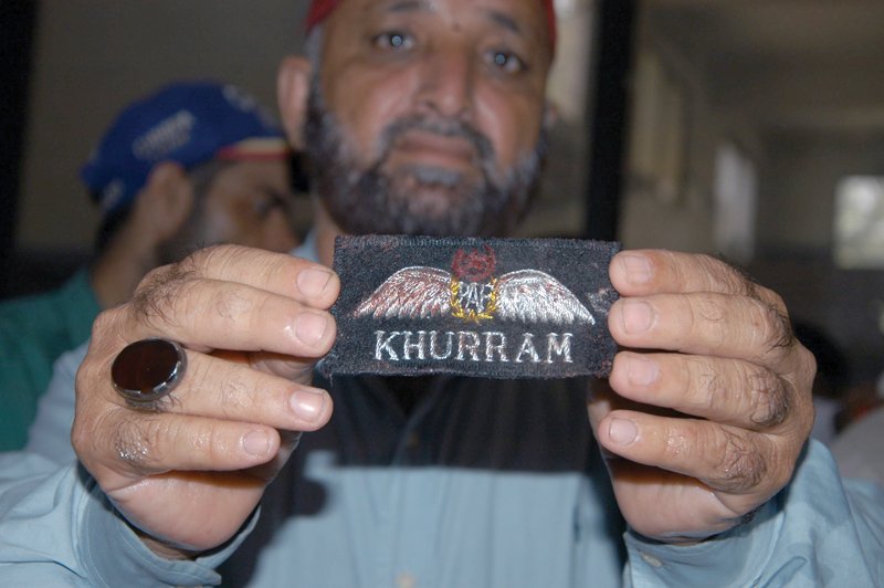 a paf official shows the badge of one of the pilots wing commander khurram sammad who was killed when the training aircraft crashed on tuesday photo mohammad saqib express