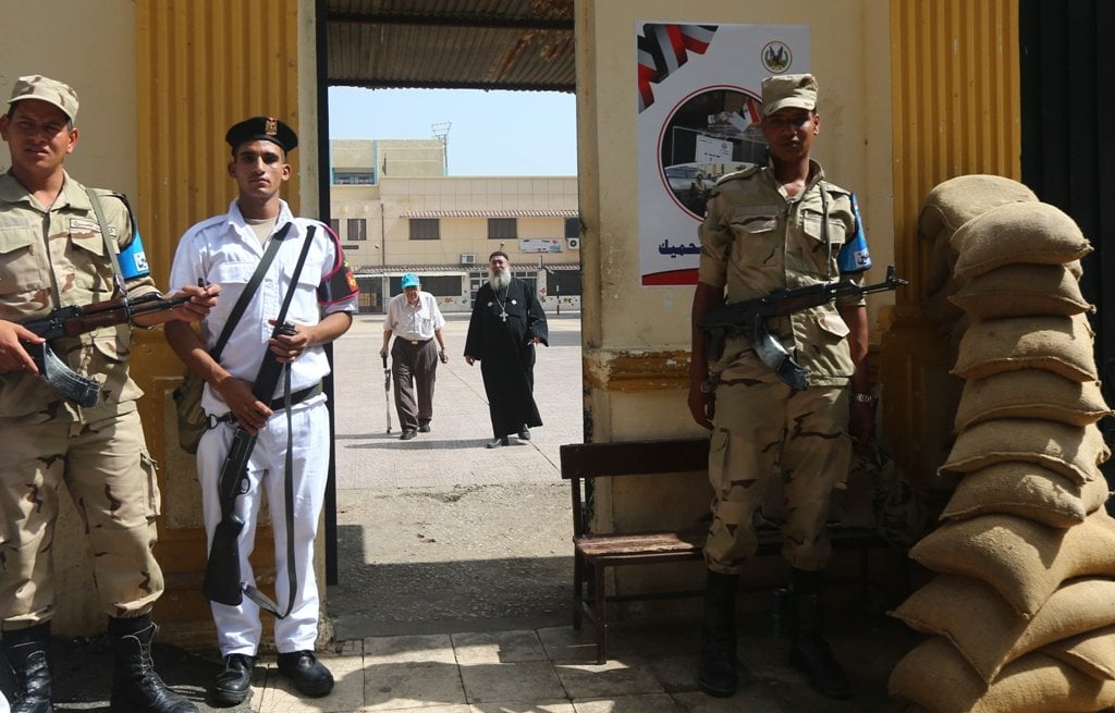 an egyptian priest c r and another christian coptic man walk out a polling station after casting their votes in cairo on the second day of egypt 039 s presidential election on may 27 2014 photo afp