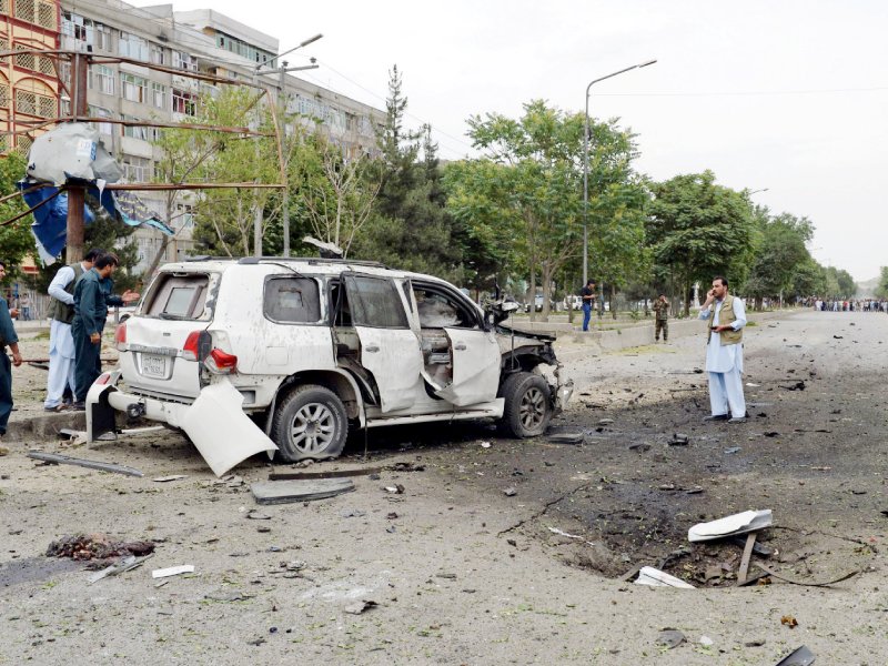 investigators inspect a damaged car at the site of a suicide car bomb attack on the convoy of presidential candidate abdullah abdullah in kabul photo afp