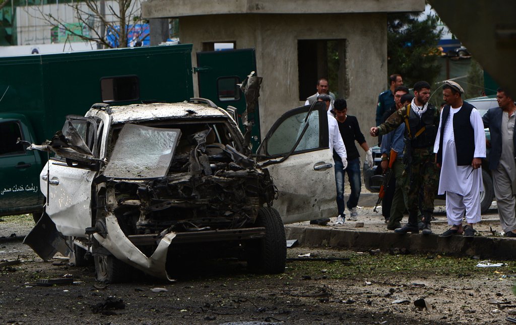 afghan investigators inspect a damaged car at the site of a suicide car bomb attack on the convoy of afghan presidential candidate abdullah abdullah as residents walk near the scene in kabul on june 6 2014 photo afp