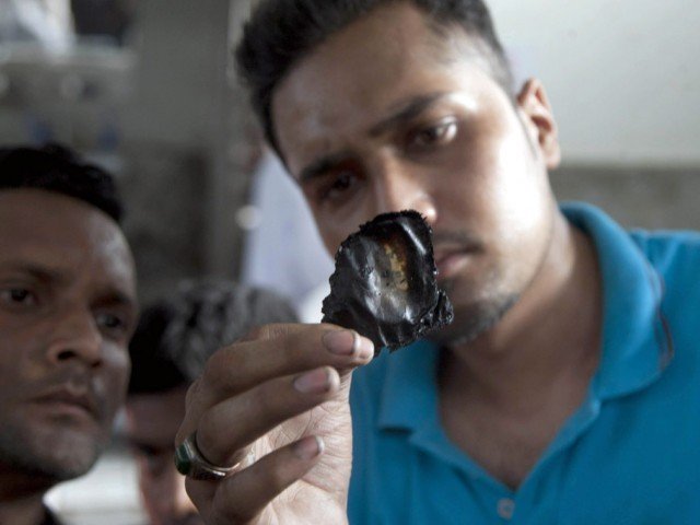 a man showing a burned identity card of one the victims who died in the cold storage facility of karachi airport photo express mohammad azeem